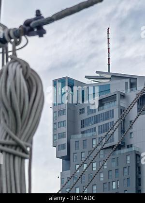 A contemporary building in Gdynia, Poland, with glass and concrete facades, is partially obscured by a soft-focused foreground of nautical ropes and c Stock Photo