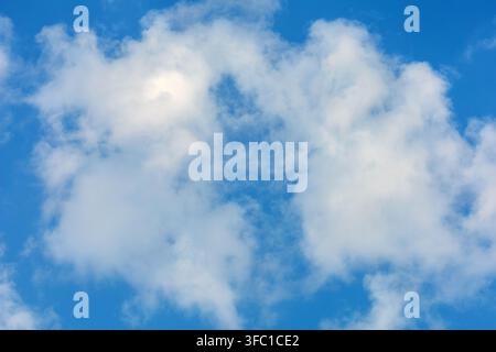 Fluffy white clouds float gently across a bright blue sky on a clear day in Spain. Stock Photo