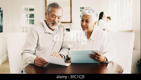 Old couple, reading and financial planning with tablet in house, happy or checking savings on report. Senior people, smile and discussion with Stock Photo