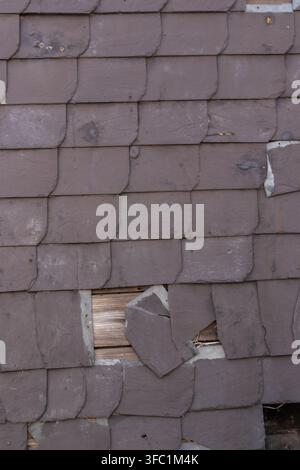 Broken slate facade or cracked slate facade with rotten and broken tiles of slate cladding show vintage house facade with need for renovation and rest Stock Photo