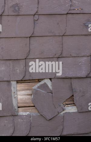 Broken slate facade or cracked slate facade with rotten and broken tiles of slate cladding show vintage house facade with need for renovation and rest Stock Photo