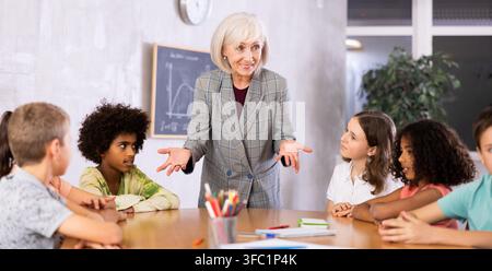 Female teacher giving kids a lesson in school classroom Stock Photo