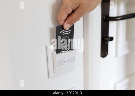 close up of a hand inserting key card into hotel room energy switch holder Stock Photo