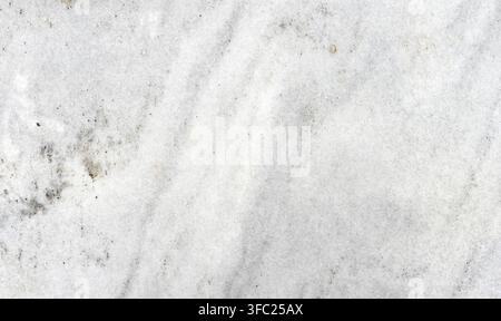 Horizontal close up view of an unpolished white granite slab with gray veins, gray and white banding, gold and silvery gray mineral clusters, and natu Stock Photo