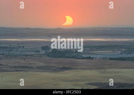 Crescent sun setting over the rural countryside of Alcaniz with wind turbines silhouetted on the horizon during the eclipse of August 12, 2026. Aragon Stock Photo