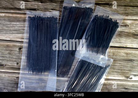 black nylon cable ties, commonly known as zip ties, used for securing wires and cables, self-locking fasteners designed for both indoor and outdoor us Stock Photo