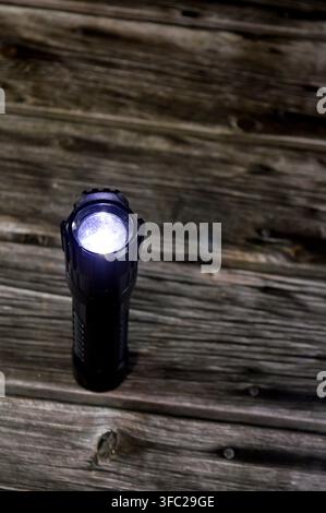 a black, high-lumen rechargeable LED tactical flashlight designed for heavy-duty outdoor use, camping, and emergency situations Stock Photo
