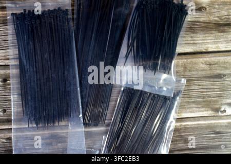 black nylon cable ties, commonly known as zip ties, used for securing wires and cables, self-locking fasteners designed for both indoor and outdoor us Stock Photo