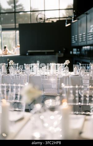 Elegant wedding dinner table setup with candles and glass chairs Stock Photo