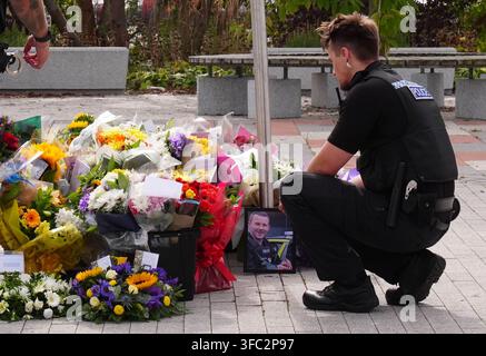Police officers look at flowers at the Cleveland Police HQ in Middlesbrough, following the line-of-duty deaths of PC Matthew Blades and PC Tom Clough who died when a car going in the wrong direction hit a police car on the A66 near Middlesbrough. Picture date: Tuesday August 25, 2026. Stock Photo