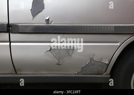 Car door paint peeling off in large flakes in a 20 year old compact car. Stock Photo