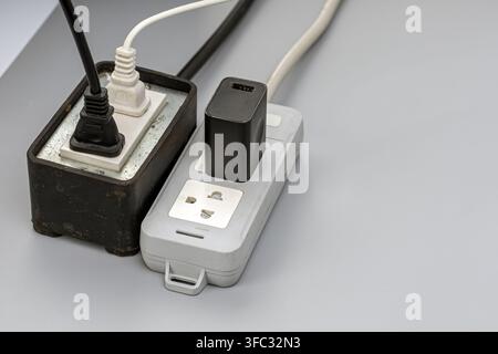 Old power strips crowded with plugs and tangled wires, highlighting electrical overload risk and dangerous wiring safety practices. Stock Photo