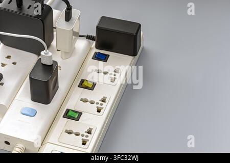 Close-up of an overloaded power strip with several plug adapters and chargers, highlighting electrical safety concerns and energy overuse. Stock Photo