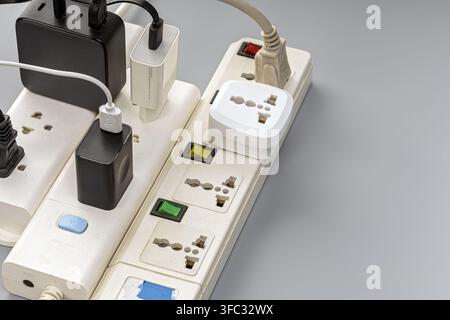 Overloaded power strip with many plugged-in chargers and adapters, showing electrical hazard and overload risk clearly. Stock Photo
