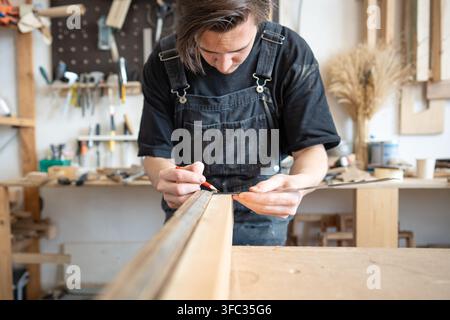 Focused skilled carpenter restorer working with vintage window frame at workplace in repair shop. Stock Photo