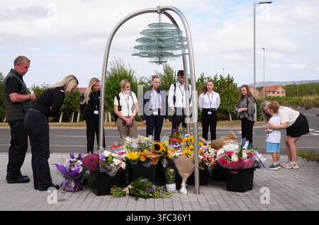 Police officers and members of the public look at flowers at the Cleveland Police HQ in Middlesbrough, following the line-of-duty deaths of PC Matthew Blades and PC Tom Clough who died when a car going in the wrong direction hit a police car on the A66 near Middlesbrough. Picture date: Tuesday August 25, 2026. Stock Photo