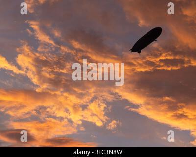 An airship blimp flying over Los Angeles set against the spectacular colors of a California sunset Stock Photo