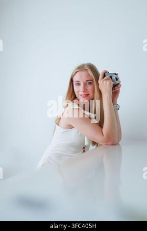 Happy female photographer posing with a retro style camera, creative profession, travel and photography concept. Stock Photo