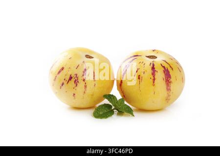 Two pepino melons with mint leaves isolated on a white background. Stock Photo