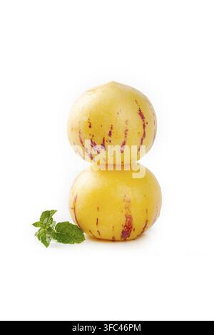 Two pepino melons stacked with mint leaves on a white background. Stock Photo