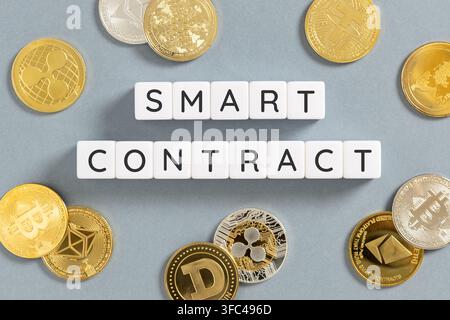 smart contract text on blocks surrounded by cryptocurrency coins Stock Photo