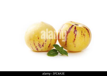 Two pepino melons with mint leaves isolated on a white background. Stock Photo