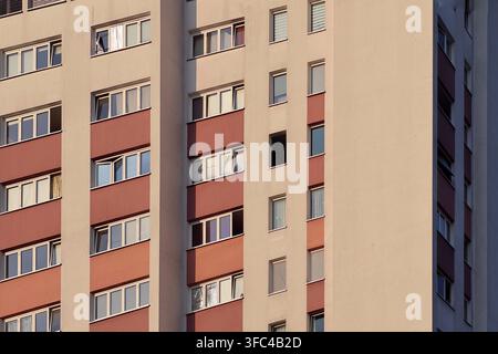 Geometric residential apartment facade with repeating windows and muted red panels Stock Photo
