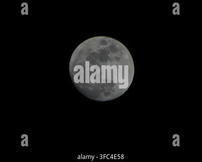 Full moon showing surface details and craters against a black night sky Stock Photo