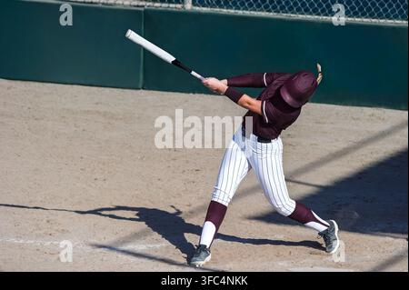 A Softball Player Is Batting And Swinging At the Ball Stock Photo