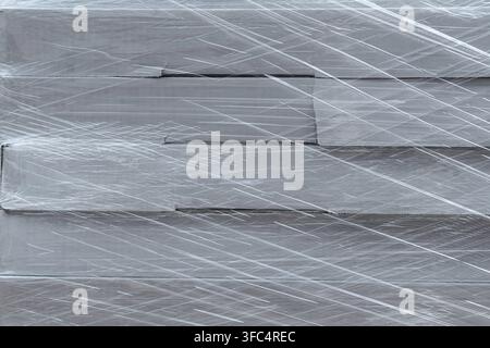 Stack of cardboard boxes wrapped in clear plastic film texture background. Stock Photo