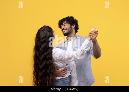 Happy Couple Dancing Together, Yellow Background, Joyful Moment Stock Photo