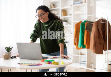 Happy Young Hispanic Woman Working On Laptop In Modern Office, Business Concept Stock Photo