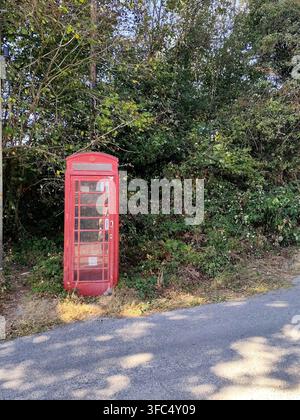 Typical K6 English phone box with its distinctive domed roof  & red-painted cast iron panels standing on a roadside in  East Sussex, UK Stock Photo