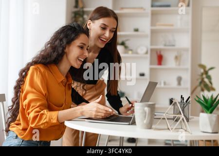 Two Smiling Women Working Together On Laptop In Modern Office, Business Concept Stock Photo