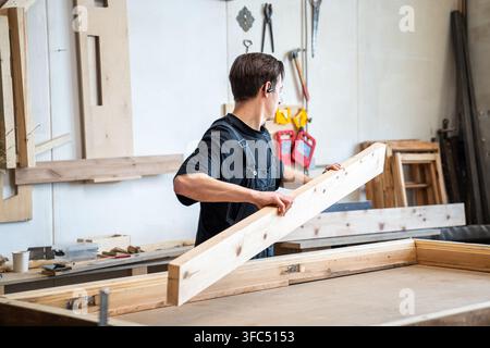 Woodworker preparing materials for antique wooden window frame restoration in woodworking studio. Stock Photo