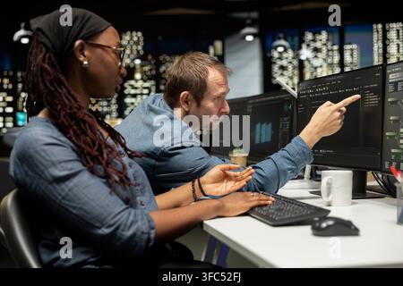 Manager assisting tech startup software developer coding AI algorithms during internship. Supervisor overseeing work done by woman in office using deep learning models to do automation Stock Photo