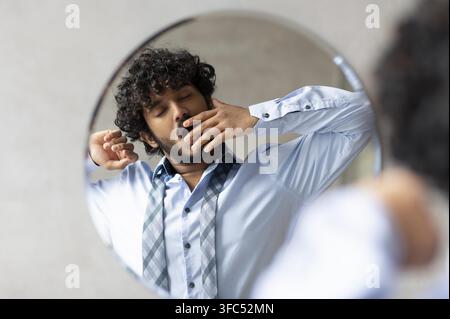 Young South Asian Man Stretching And Yawning In Front Of Mirror, Morning Routine Stock Photo
