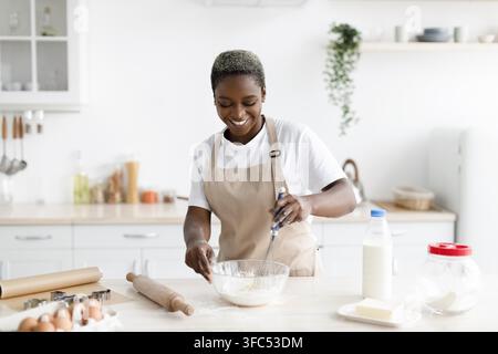 Happy Black Female Baker Mixing Dough In Modern Kitchen, Homemade Cooking Concept Stock Photo