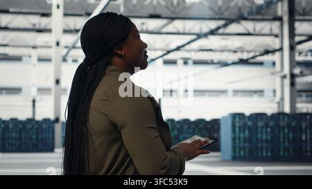 Manager in data center using tablet to coordinate deployment of new server architecture. Server farm IT expert using device to do rollout of cybersecurity framework, protecting data, camera B Stock Photo