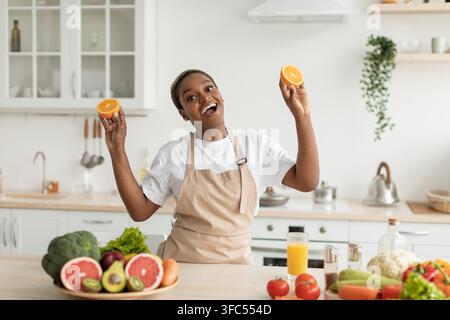 Happy Black Woman Holding Fresh Oranges In Kitchen, Healthy Eating Concept Stock Photo