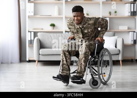 Young African American Man In Wheelchair Expressing Pain At Home, Healthcare Concept Stock Photo