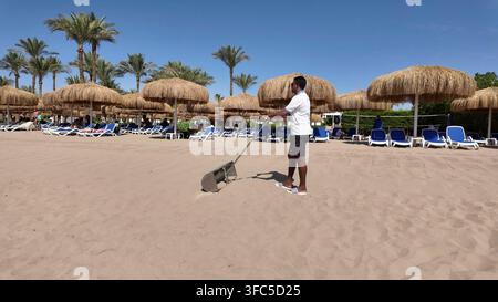 SHARM EL SHEIKH, EGYPT - JUN 10, 2026: A staff member cleaning the beach sand with a rake tool at a resort in Sharm El Sheikh. Stock Photo