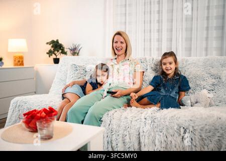 Mother and daughters relaxing on sofa watching tv together Stock Photo