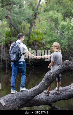 Two men shaking hands over a river, with a backpack nearby, suggesting an outdoor adventure or a business meeting in a scenic location. Stock Photo