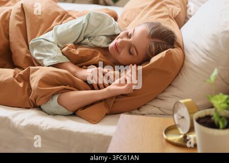 Restful sleep and morning routine, young woman sleeping peacefully in bed with soft bedding and natural light Stock Photo