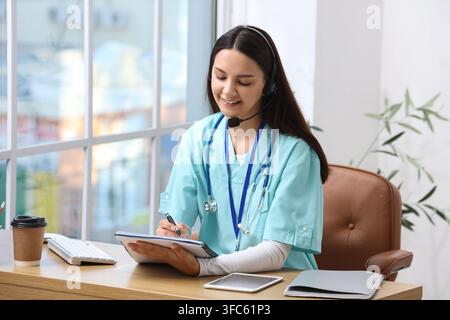 Telemedicine and virtual healthcare, young female doctor or nurse with headset consulting online, medical support and remote patient care Stock Photo