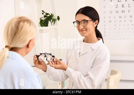 Eye care and vision health, optometrist holding trial frame for patient during eye exam in clinic Stock Photo