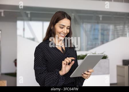 Smiling businesswoman browsing content on digital tablet Stock Photo