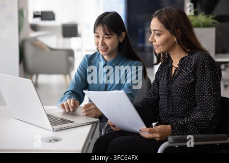 Two diverse women collaborating on project or presentation in office Stock Photo