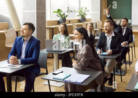 Happy business team attending corporate workshop with coach in modern classroom Stock Photo